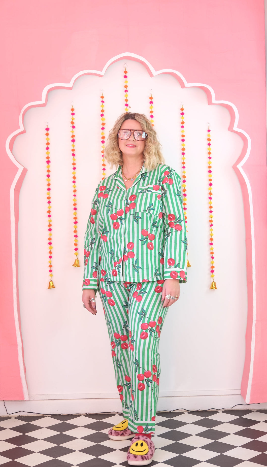 Person wearing a green pajama set with red cherries on a pink background