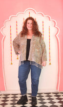 Load image into Gallery viewer, Person wearing a patterned jacket and blue jeans standing on a pink and white checkered floor.